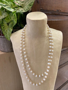 A long ladies necklace made from soft white iridescent beads attached to gold metal loops. Fastens with a clasp. Nickel free.