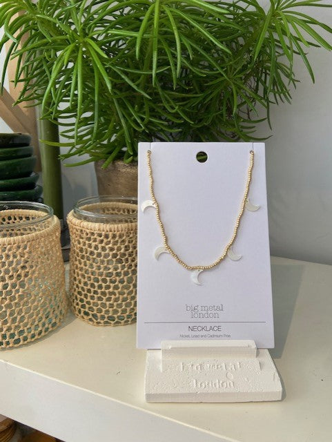 Mother of pearl moon shaped charms on a gold beaded fine necklace, with clasp fastening and extender chain. Big Metal London. 