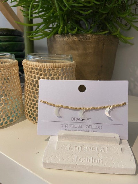 A dainty gold beaded bracelet adorned with mother of pearl moon charms. Fastened with a clasp and with extender chain. 