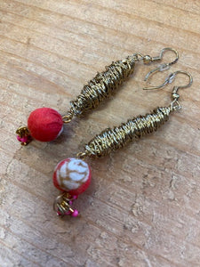 Handmade earrings,using gold coloured wire intricately wound round to create a drop pendant. To the base is a fabric covered bead in red using recycled sari's. To the base of this are bright pink tiny beads which dangle and move. 