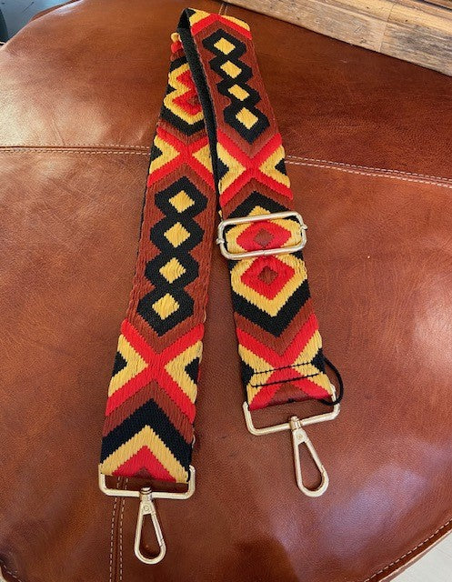 A detachable and adjustable bag strap. In a woven aztec design in shades of red, black and a gold toned yellow. With gold hardware. Style up your handbag with your own unique look. 