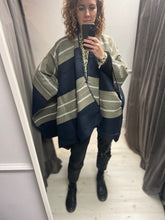 Load image into Gallery viewer, This ladies cape is oversized and supersoft. With a shaped neckline, it simply drapes over your shoulders. With no fixed armholes it is so easy to wear. In a navy bold stripe and a navy blanket stitch to the edges. It is one size.