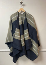 Load image into Gallery viewer, This ladies cape is oversized and supersoft. With a shaped neckline, it simply drapes over your shoulders. With no fixed armholes it is so easy to wear. In a navy bold stripe and a navy blanket stitch to the edges. It is one size. 