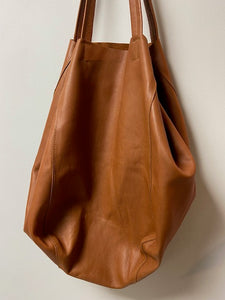 A beautiful tan leather handbag handmade in Marrakech. Morocco. It is a sizeable bag slouchy in nature. The inner leather ties can be secured to make the bag smaller, or keep them loose and the bag is large and spacious. With an inner zipped pocket and inner pockets.